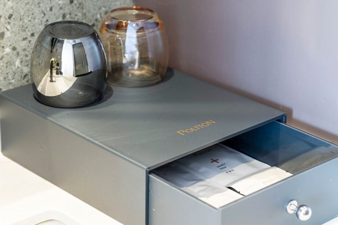 A metallic object with the word 'POLTON' on it, a transparent glass object, and a drawer with a visible lock mechanism.
