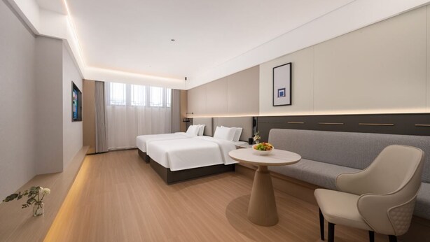 Ein Hotelzimmer mit Bett, Sofa, rundem Tisch und Stuhl.