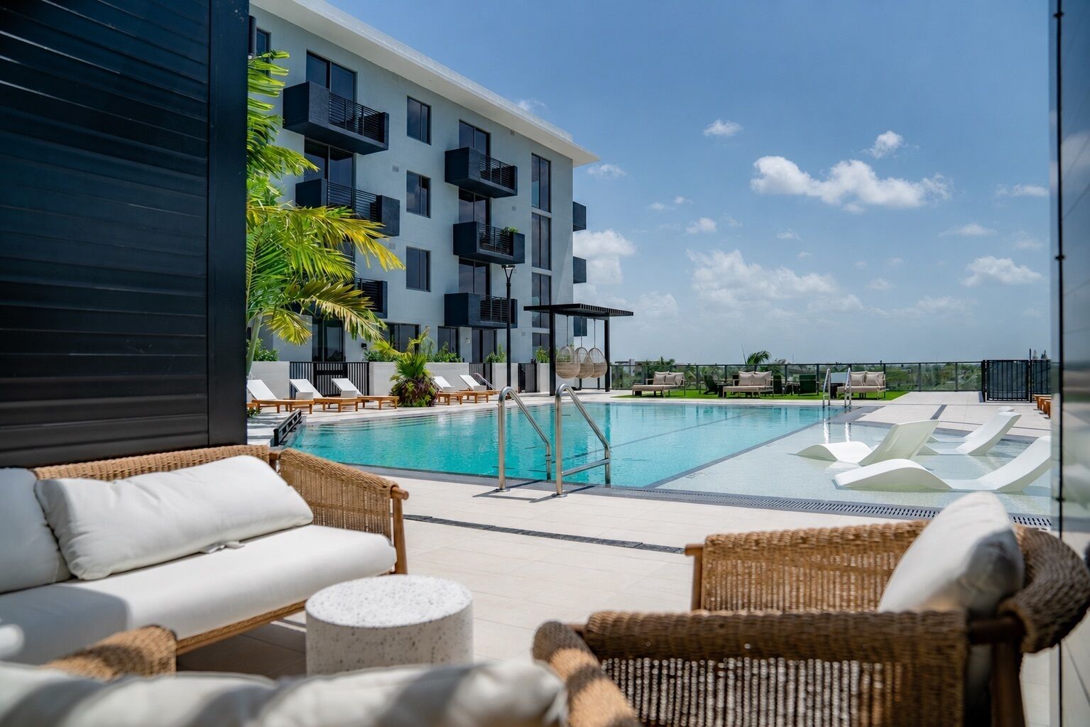 A rooftop pool area with lounge chairs, a swimming pool, and a building with balconies.
