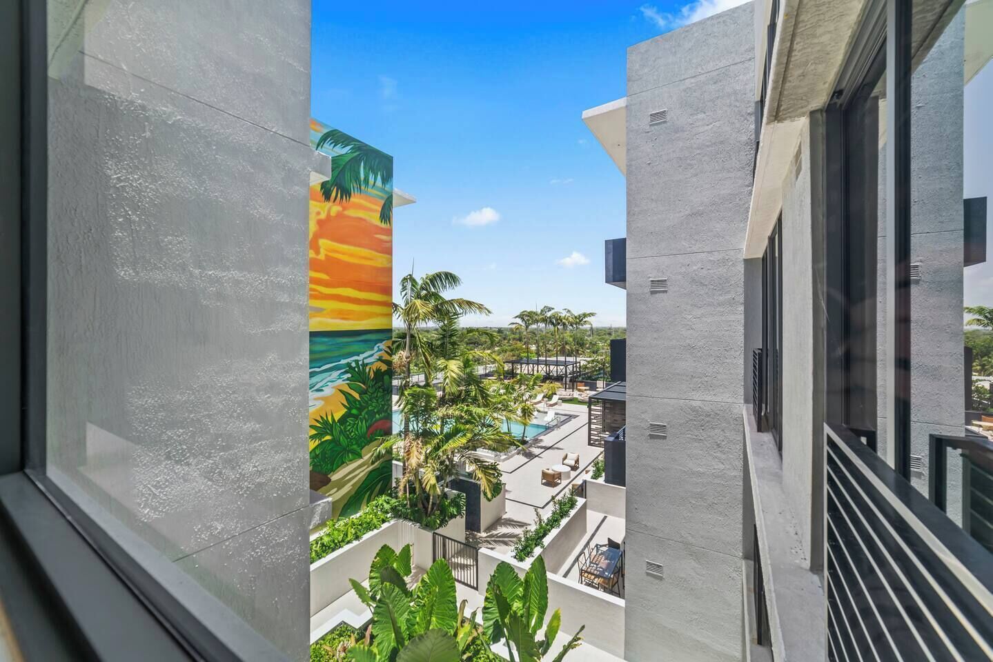 A modern building with a view of a pool area and a painted mural of a sunset.