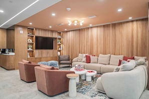 A modern living room with a sofa set, a coffee table, and a television mounted on the wall.