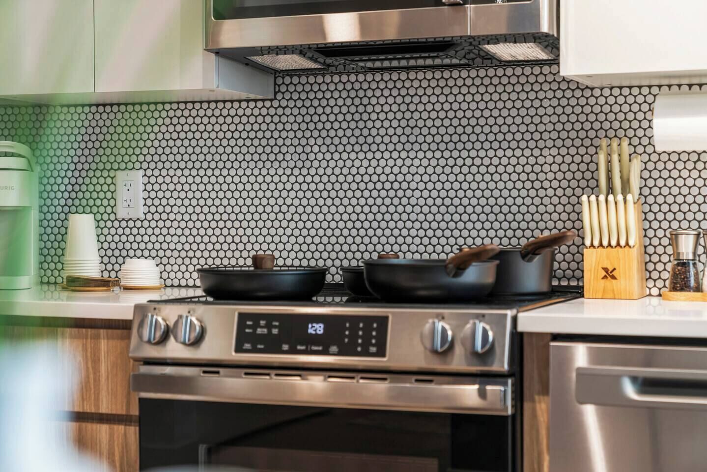 Una cucina con piano cottura in acciaio inossidabile, forno a microonde e zoccolo a mosaico.