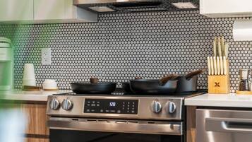Una cucina con piano cottura in acciaio inossidabile, forno a microonde e zoccolo a mosaico.