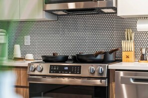 Una cocina con estufa de acero inoxidable, microondas y salpicadero de azulejos.