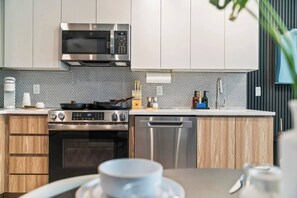 Una cocina moderna con electrodomésticos de acero inoxidable, microondas, estufa y lavavajillas.