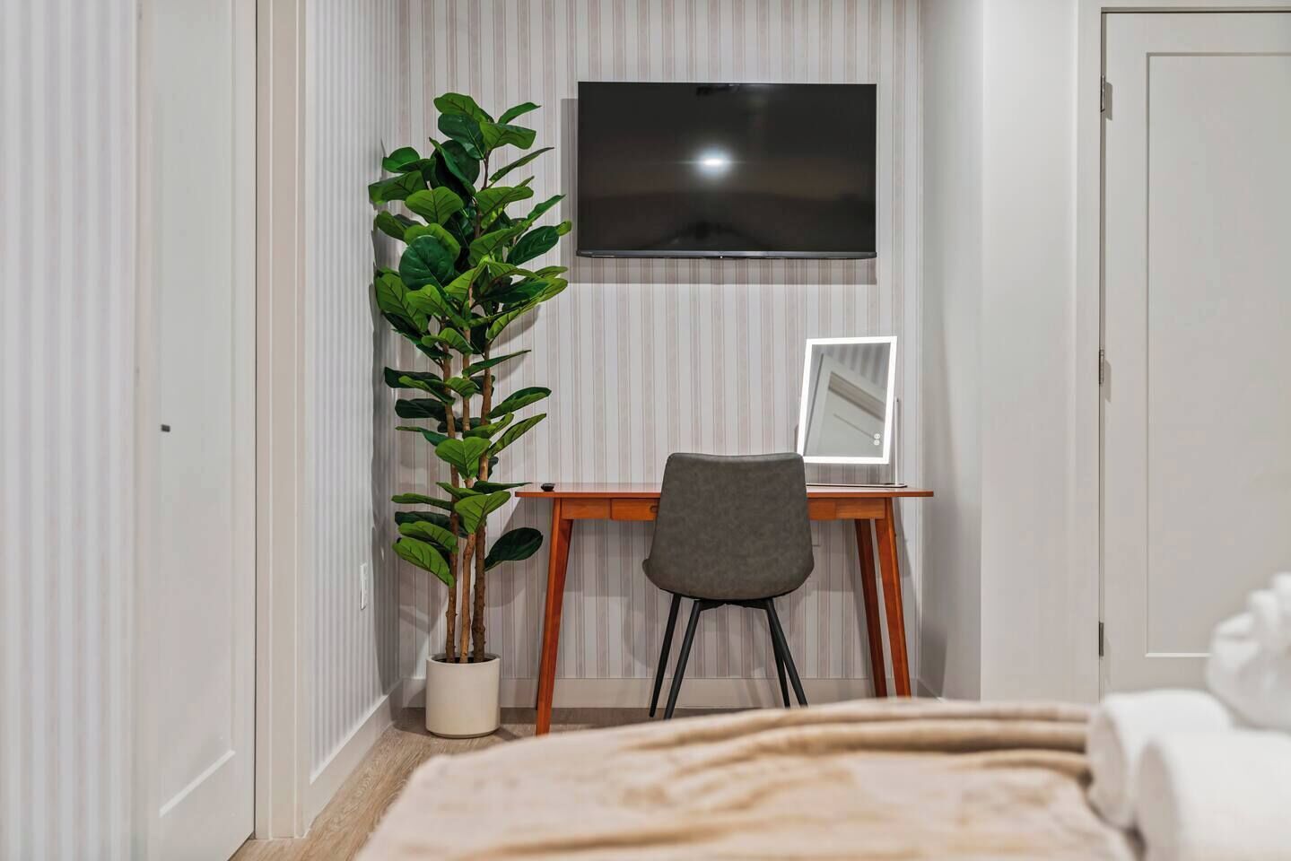 Una camera da letto con un letto, una scrivania con una sedia, una televisione e una pianta in vaso.