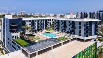 A modern building with a rooftop pool, multiple balconies, and a view of the city skyline.