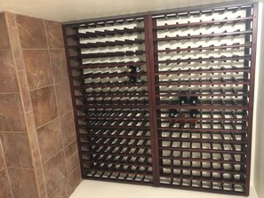 Ein Weinkühlschrank mit mehreren Fächern, eine geflieste Wand und ein weißer Boden.