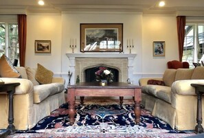 A room with a fireplace, two sofas, a coffee table, and a patterned rug. - Grand Craftsman Estate built in 1937 Charms in the heart of Carmel By The Sea (Carmel)