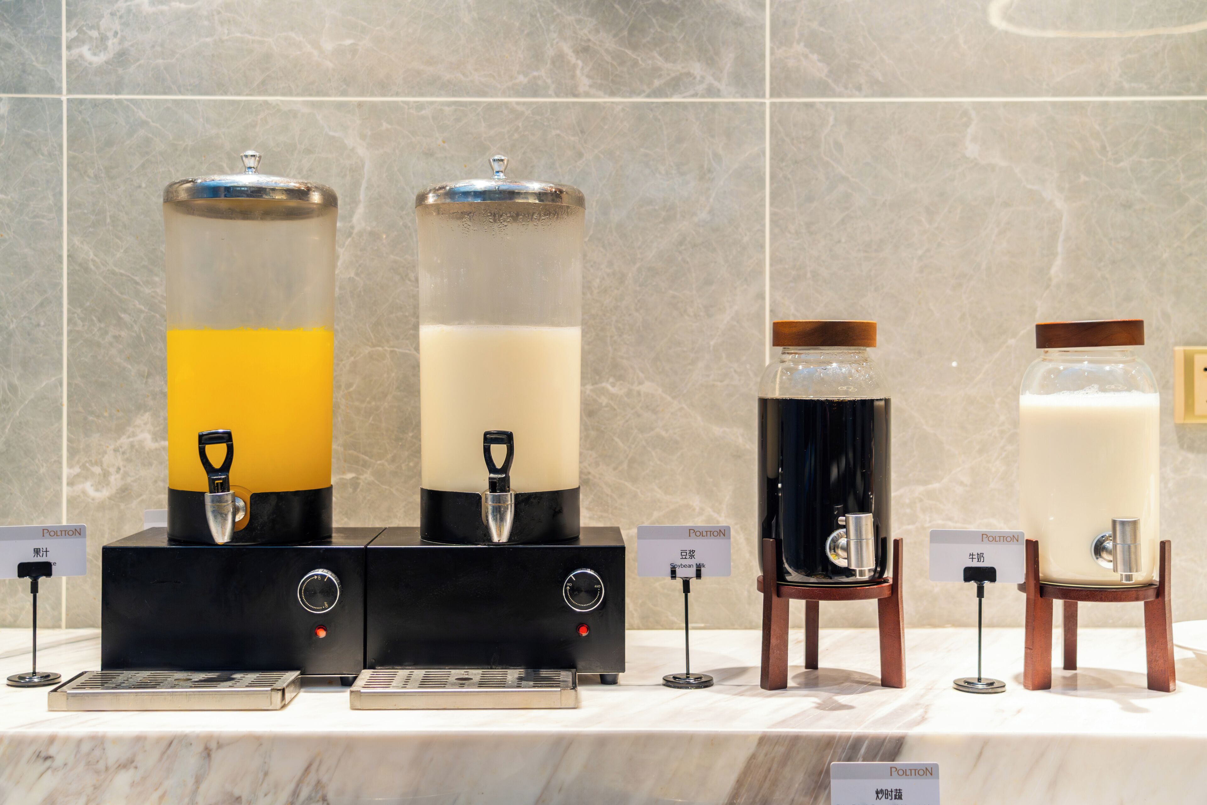 Four beverage dispensers with labels indicating different drinks.