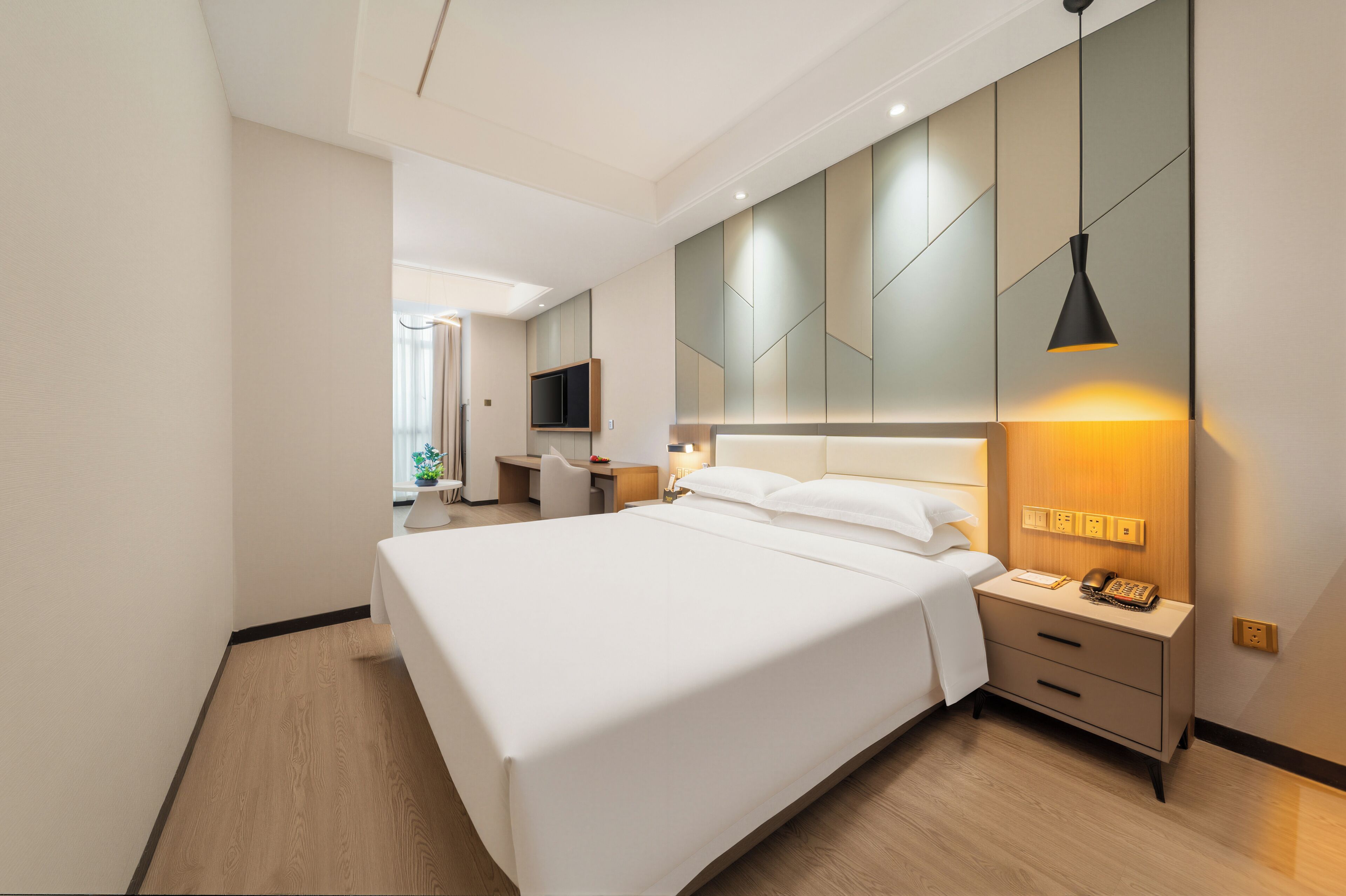 A modern hotel room with a large bed, bedside tables, a desk, and a television.