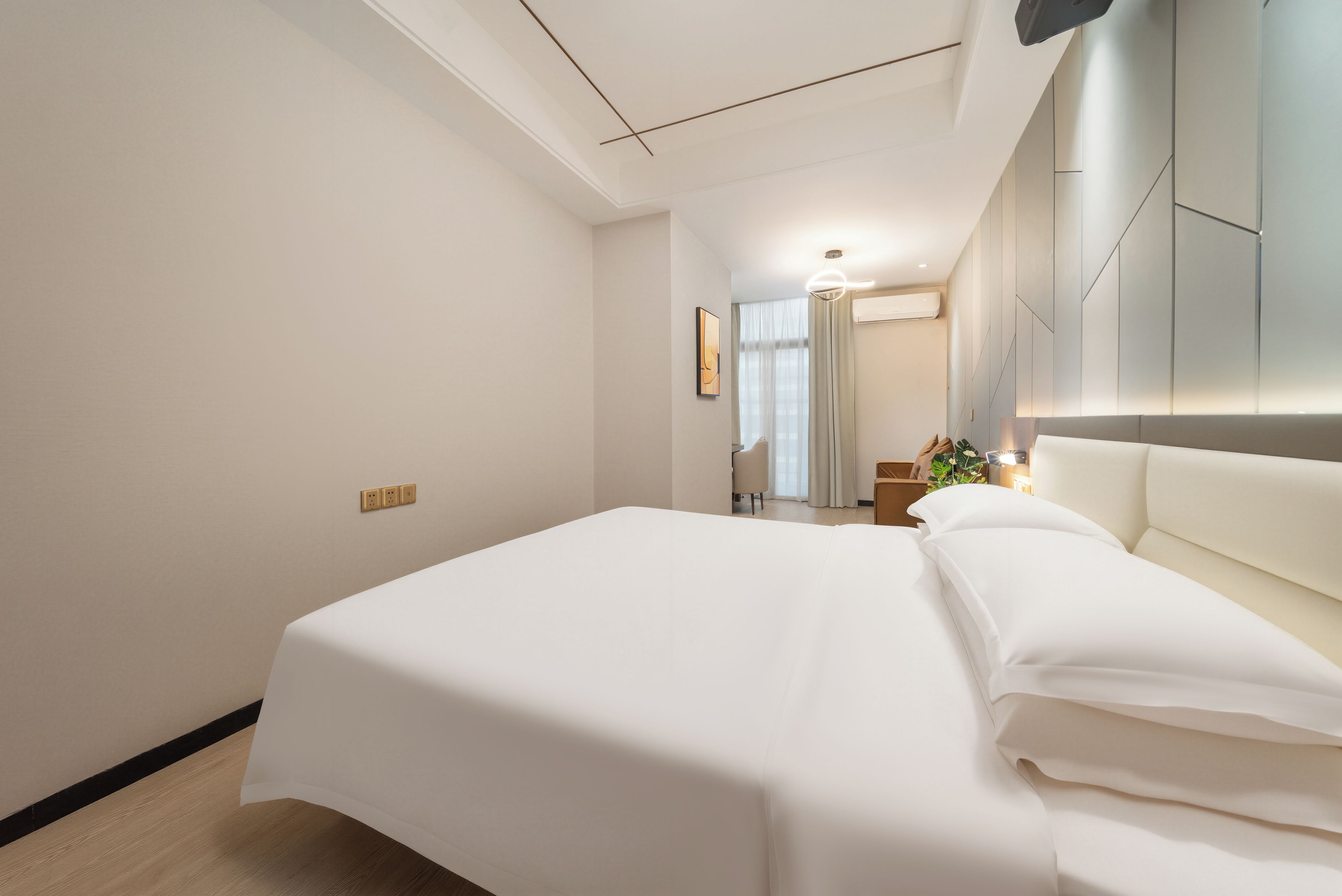 A hotel room with a large bed, a bedside table, a mirror, and a view of the hallway.