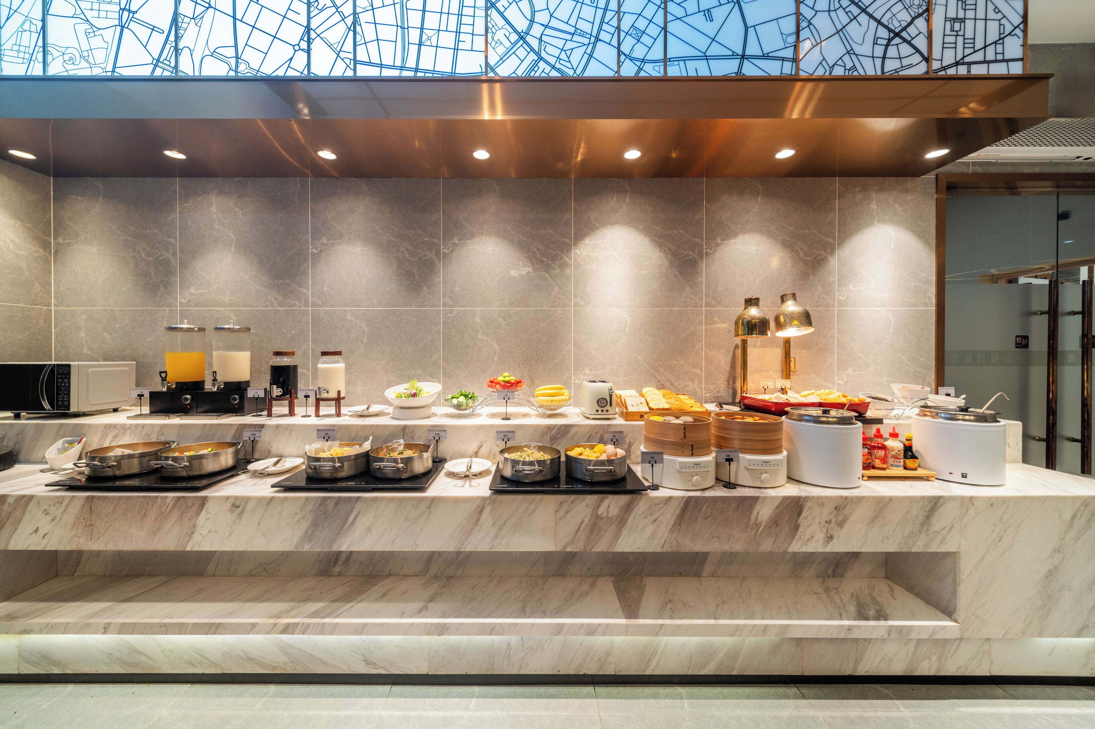 A buffet setup with various food items and cooking appliances.
