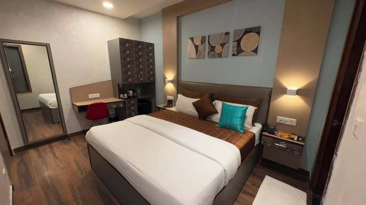 A hotel room with a large bed, a desk, a wardrobe, and a mirror.