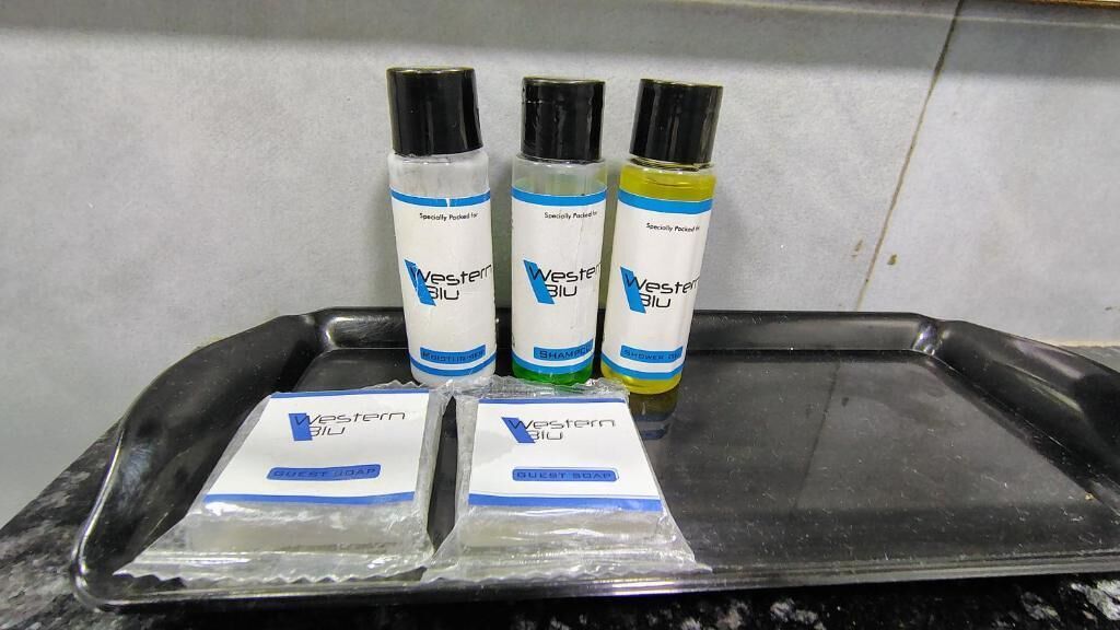 Een dienblad met vier flessen Western Blue shampoo en twee zeepjes voor gasten.