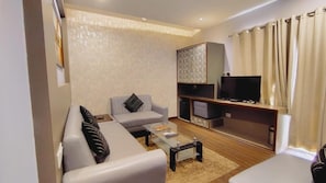 Una sala de estar con sofá, una mesa de centro, televisor de pantalla plana y un mueble.