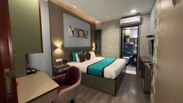 A hotel room with a bed, a desk, a chair, and a bathroom visible through an open door.