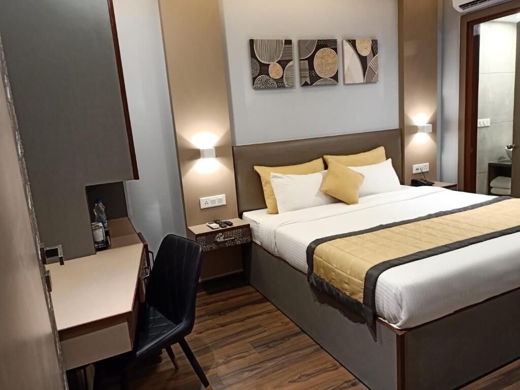 A hotel room with a bed, bedside table, chair, and a desk.