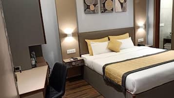 A hotel room with a bed, bedside table, chair, and a desk.