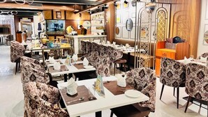 Un interior de restaurante con varias mesas, sillas y una zona de barra.