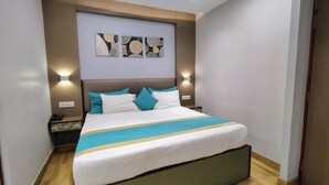Una habitación de hotel con una cama grande, un cabecero, dos mesitas de noche e iluminación empotrada en la pared.