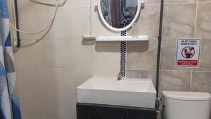 Un bagno con un lavandino bianco, un water e un cartello che vieta di gettare la carta igienica nel water.