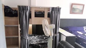 A room with a bunk bed, a standing fan, a black leather couch, and a framed picture on the wall. - Room-cozy Deluxe Guest Room in South Pat (Pattaya)