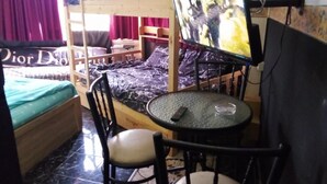 Ein Zimmer mit einem Etagenbett, einem runden Tisch mit Stühlen, einem Bett mit grüner Bettdecke und einem Poster an der Wand.