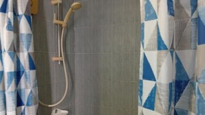 Ein Duschbereich mit Handbrause und am Wand montiertem Wasserhahn.