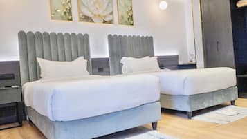 Habitación de hotel moderna con dos camas, un ventanal grande y un televisor de pantalla plana.