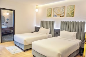 A hotel room with two beds, a bathroom, and three wall-mounted artworks.