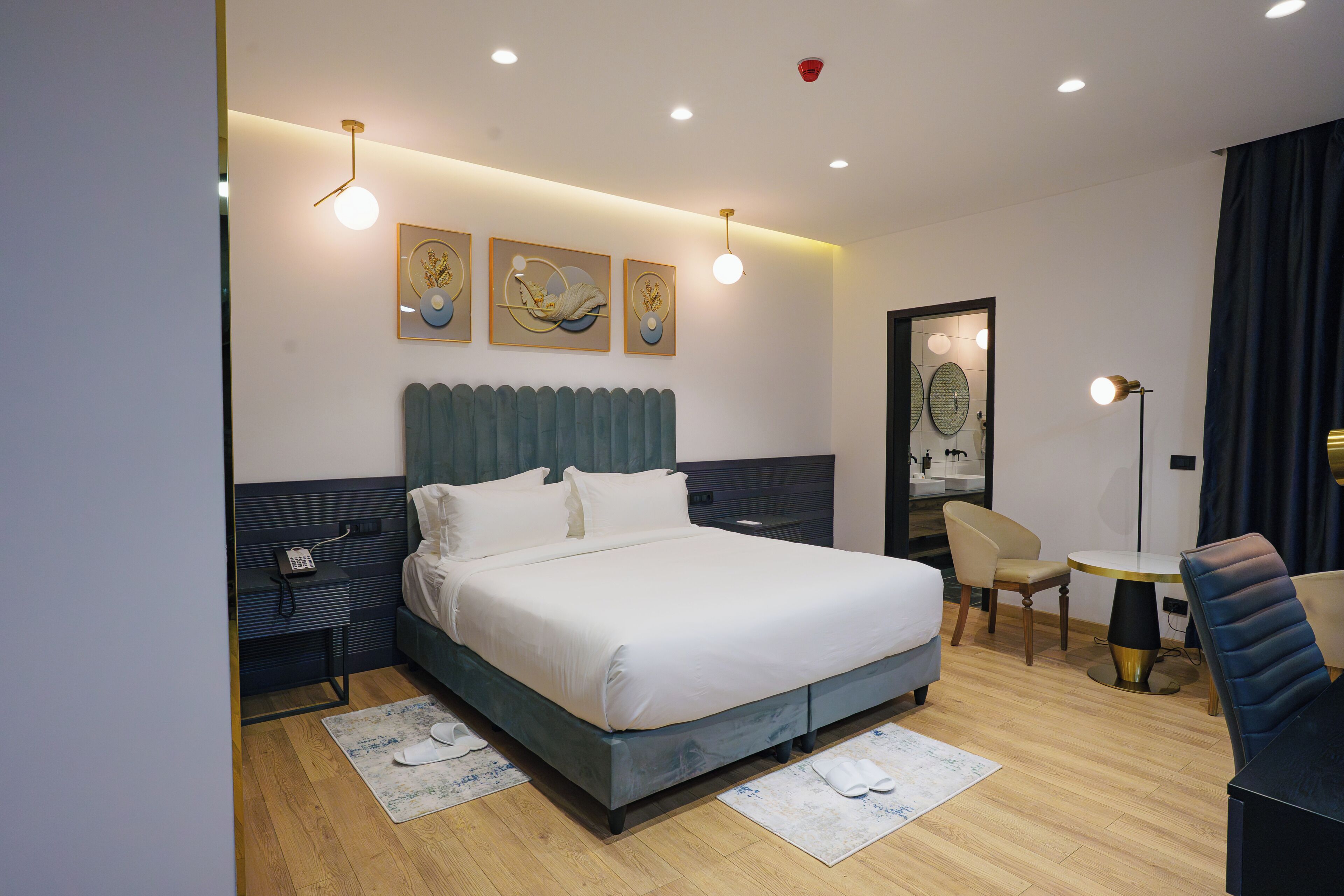 A modern hotel room with a large bed, bedside tables, a desk, and a chair.