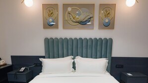 Un dormitorio moderno con una cama grande, dos mesitas de noche, un cabecero y una obra de arte colgada en la pared.