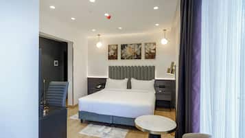 Una habitación de hotel moderna con una cama grande, un escritorio, una silla y una mesa redonda.
