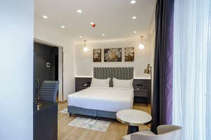 Una habitación de hotel moderna con una cama grande, un escritorio, una silla y una mesa redonda.