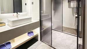 A modern bathroom with a large mirror, a white sink, and a glass-enclosed shower area. - Poltton International Service Apartment (Liuzhou Yaobu Ancient Town Chengzhong Wanda Plaza) (Liuzhou)