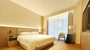 A hotel room with a large bed, bedside tables, a chair, and a desk with a lamp. - Poltton International Service Apartment (Liuzhou Yaobu Ancient Town Chengzhong Wanda Plaza) (Liuzhou)