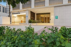A modern building entrance with a glass facade, a visible fire hydrant, and a sign indicating a parking area.
