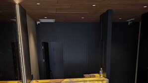 A reception desk with a marble-like surface, a dark wall with vertical lines, and a tiled floor. - Tanyel Hotel (Istanbul)