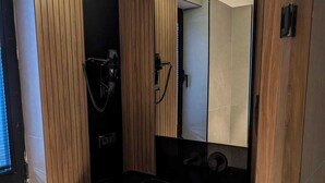 A modern bathroom with a black countertop, wooden paneling, and a large mirror. - Tanyel Hotel (Istanbul)