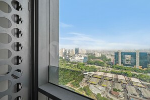 Ein Stadtbild durch ein Fenster mit runden Ausschnitten, moderne Gebäude und Grünflächen.