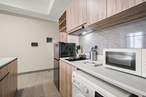 Eine moderne Küche mit Holzschränken, einer eingebauten Mikrowelle und einer Waschmaschine.
