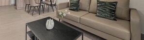 A modern living room with a sofa, a coffee table, and a dining area with chairs. - Romel by Kozystay - Kemayoran (Jakarta)