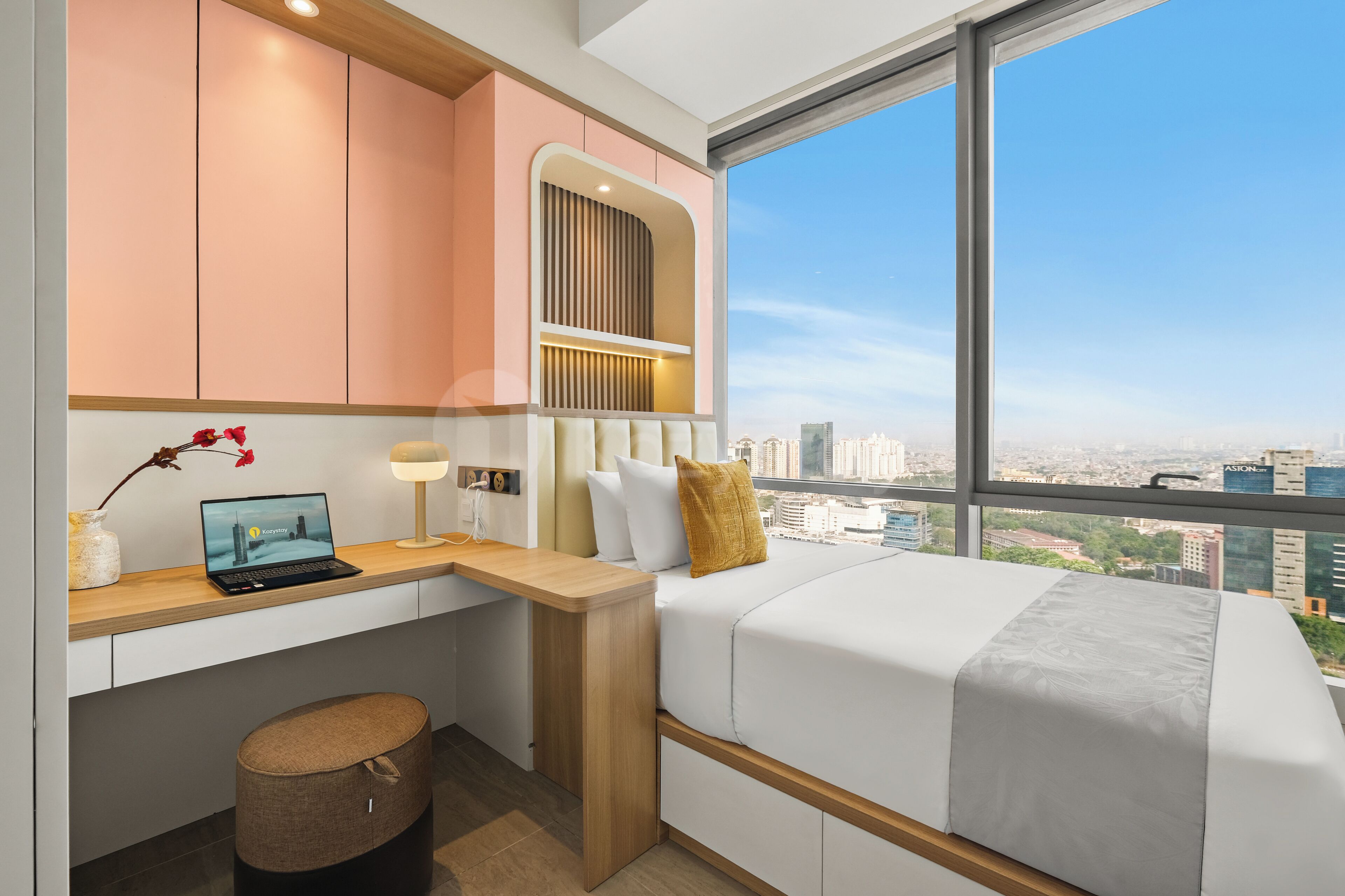 Ein modernes Hotelzimmer mit Bett, Schreibtisch und Blick auf die Stadtlandschaft.