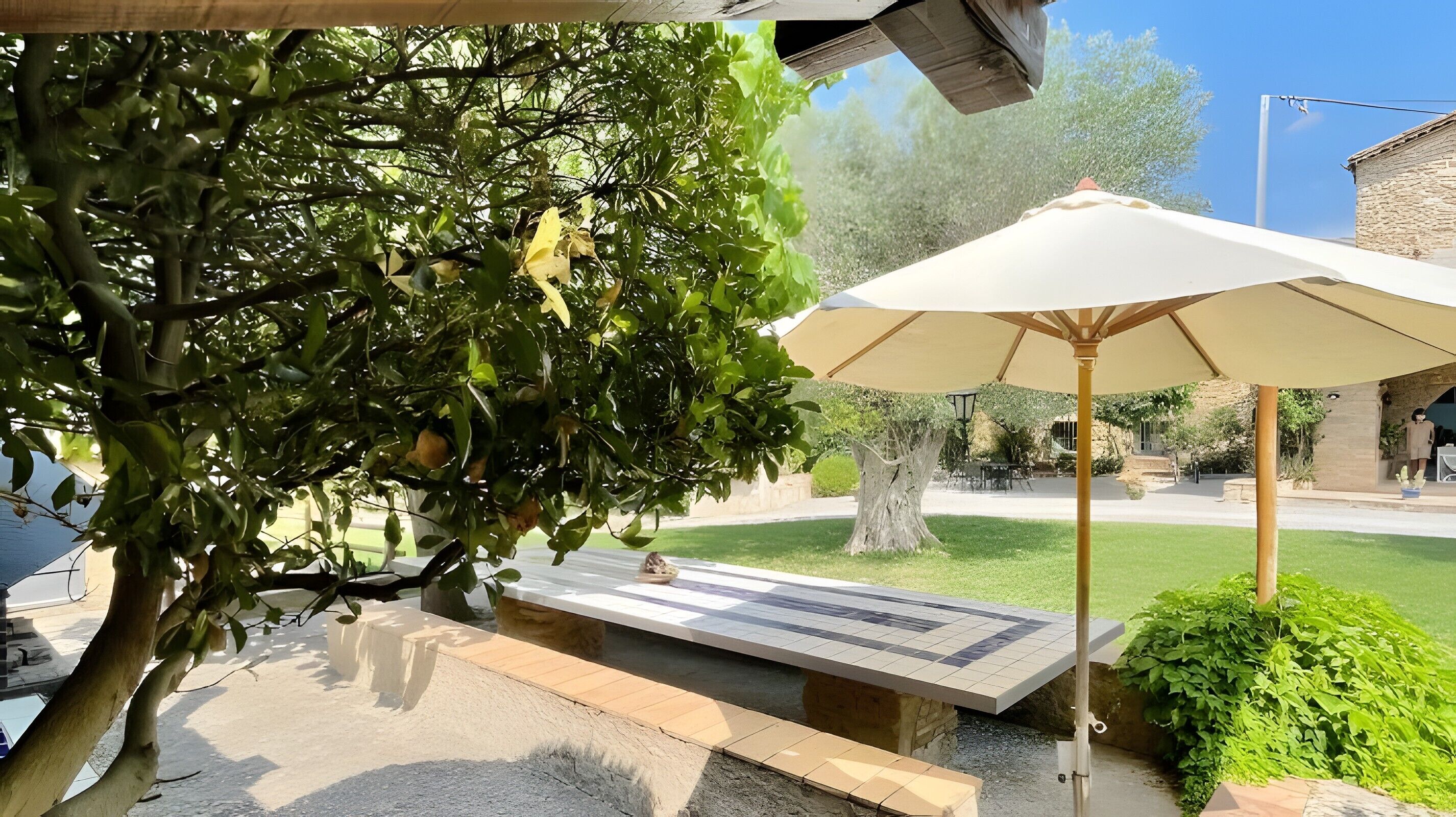 Un espacio de estar al aire libre con un banco, una mesa y un paraguas grande.