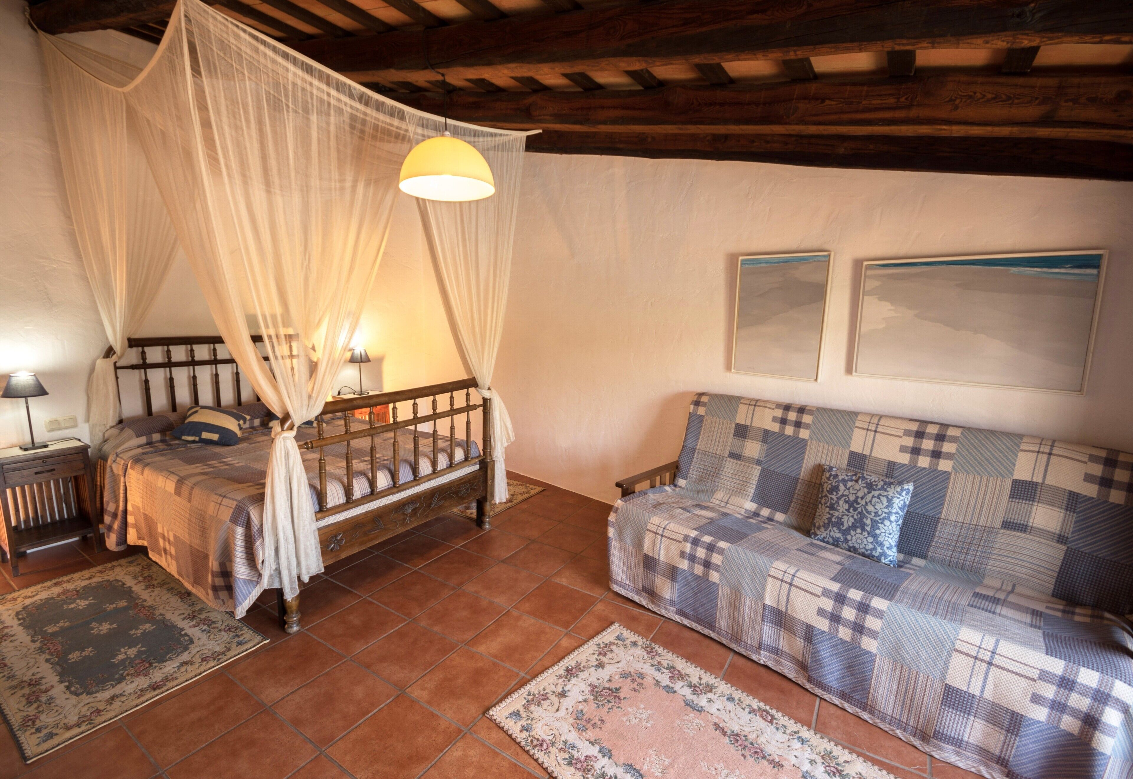 Ein Schlafzimmer mit Himmelbett, einer Couch und zwei gerahmten Bildern an der Wand.
