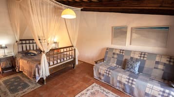 Ein Schlafzimmer mit Himmelbett, einer Couch und zwei gerahmten Bildern an der Wand.