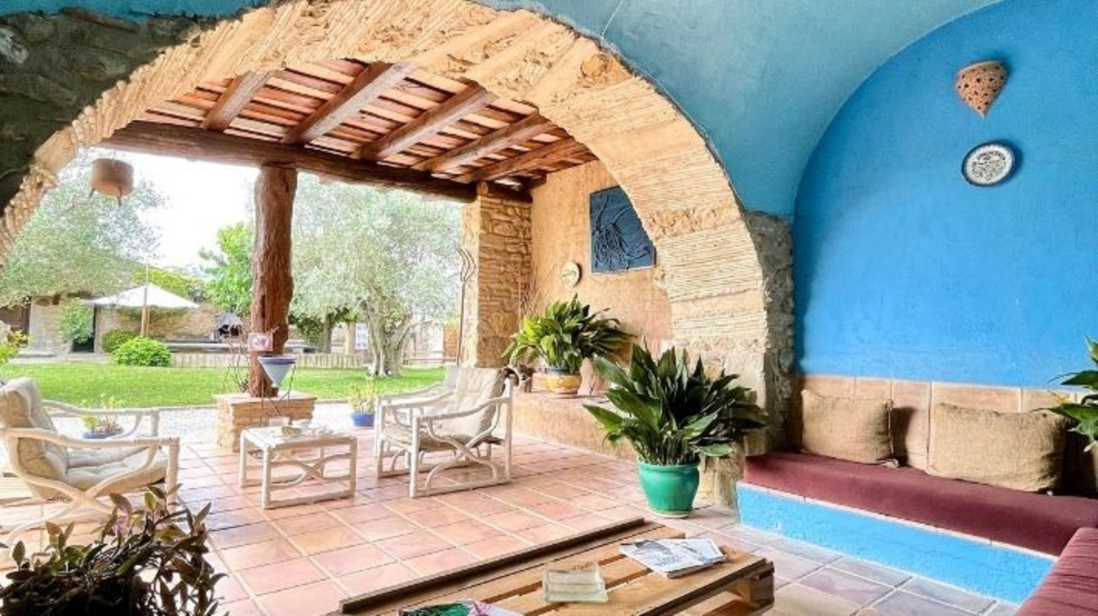Un espace extérieur aménagé en terrasse, avec une pergola en bois, des sièges et des plantes en pot.