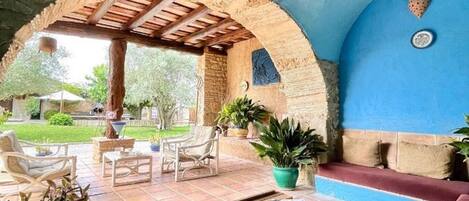 An outdoor patio area with a wooden pergola, seating, and potted plants.