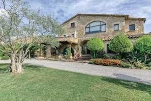 A stone building with a covered patio, a gravel driveway, and well-maintained landscaping. - Two 18th-century country houses 'Can Gat Vell' with private pool, Wi-Fi, AC, fans (LLAMPAIES)